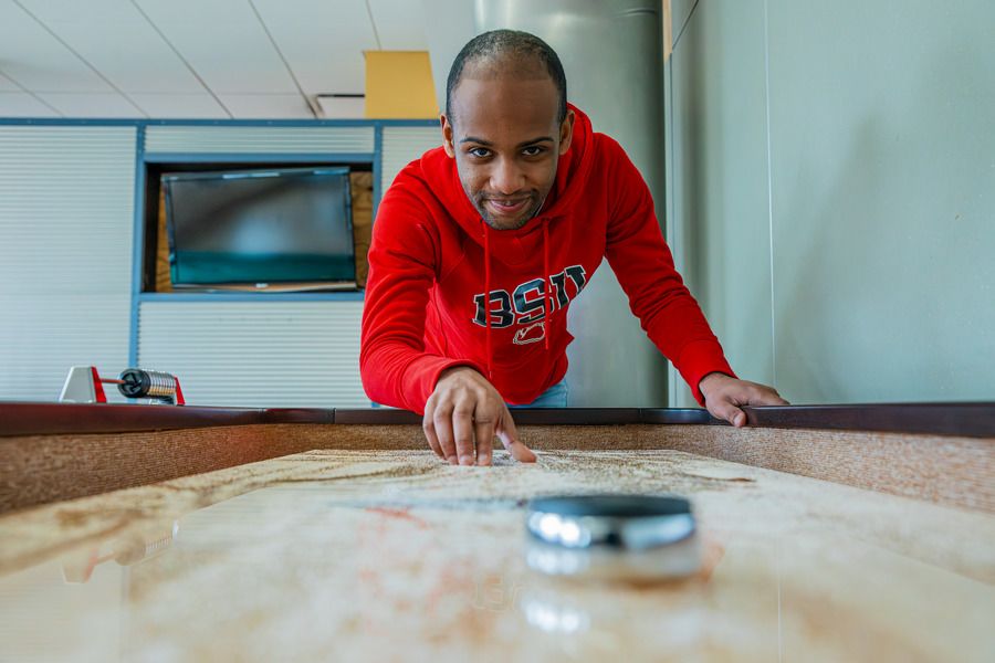 A student plays a tabletop game in a residence hall lounge.
