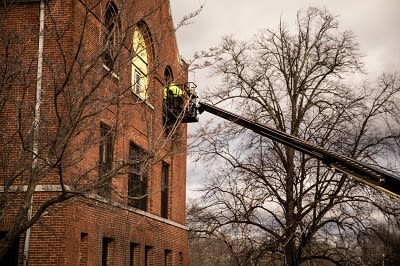 A worker uses a lift to replace Art Center windows.