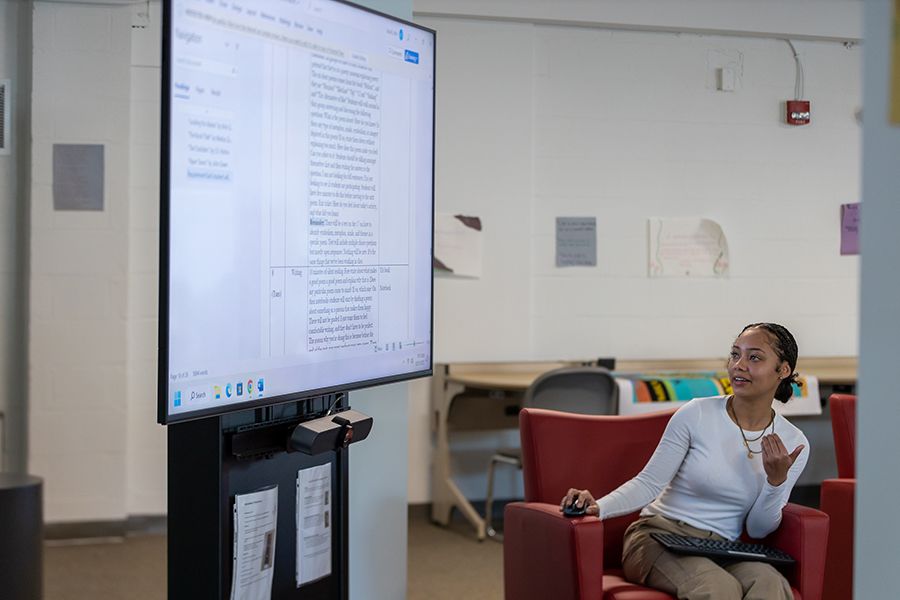 A student talks while looking at a large monitor in the Humanities Lounge.