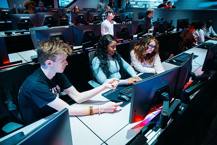 In the cyber range, three students work collaboratively while sitting at a computer.