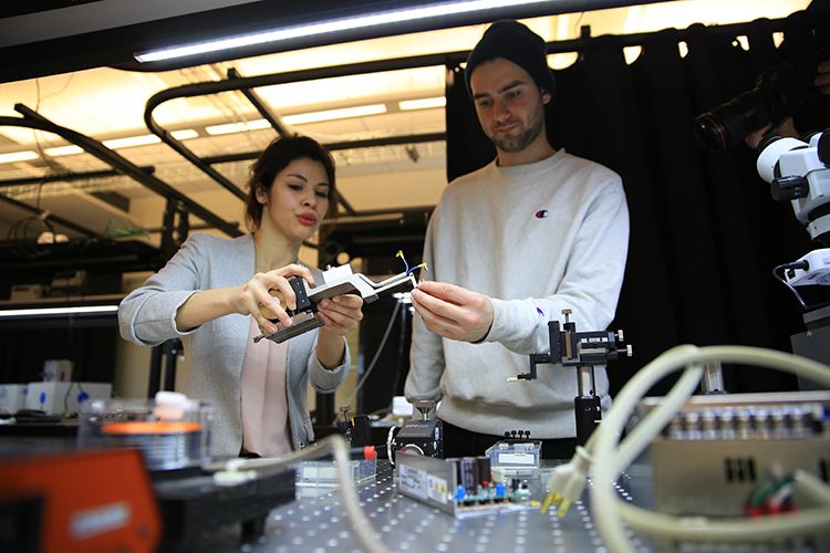 A professor and a student work together on equipment in a photonics lab.