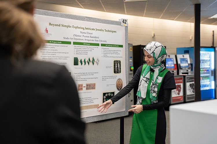 A student presents an academic poster at a conference.