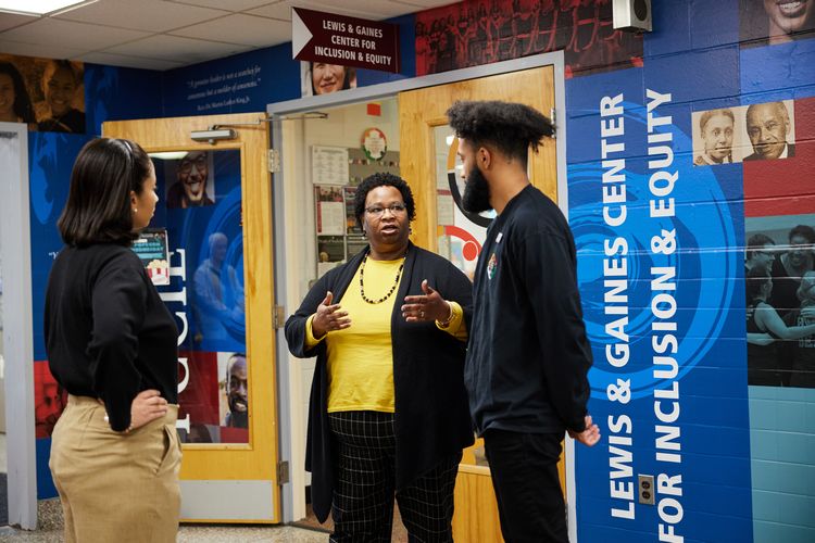 Three people converse while standing in a hallway outside of LGCIE.
