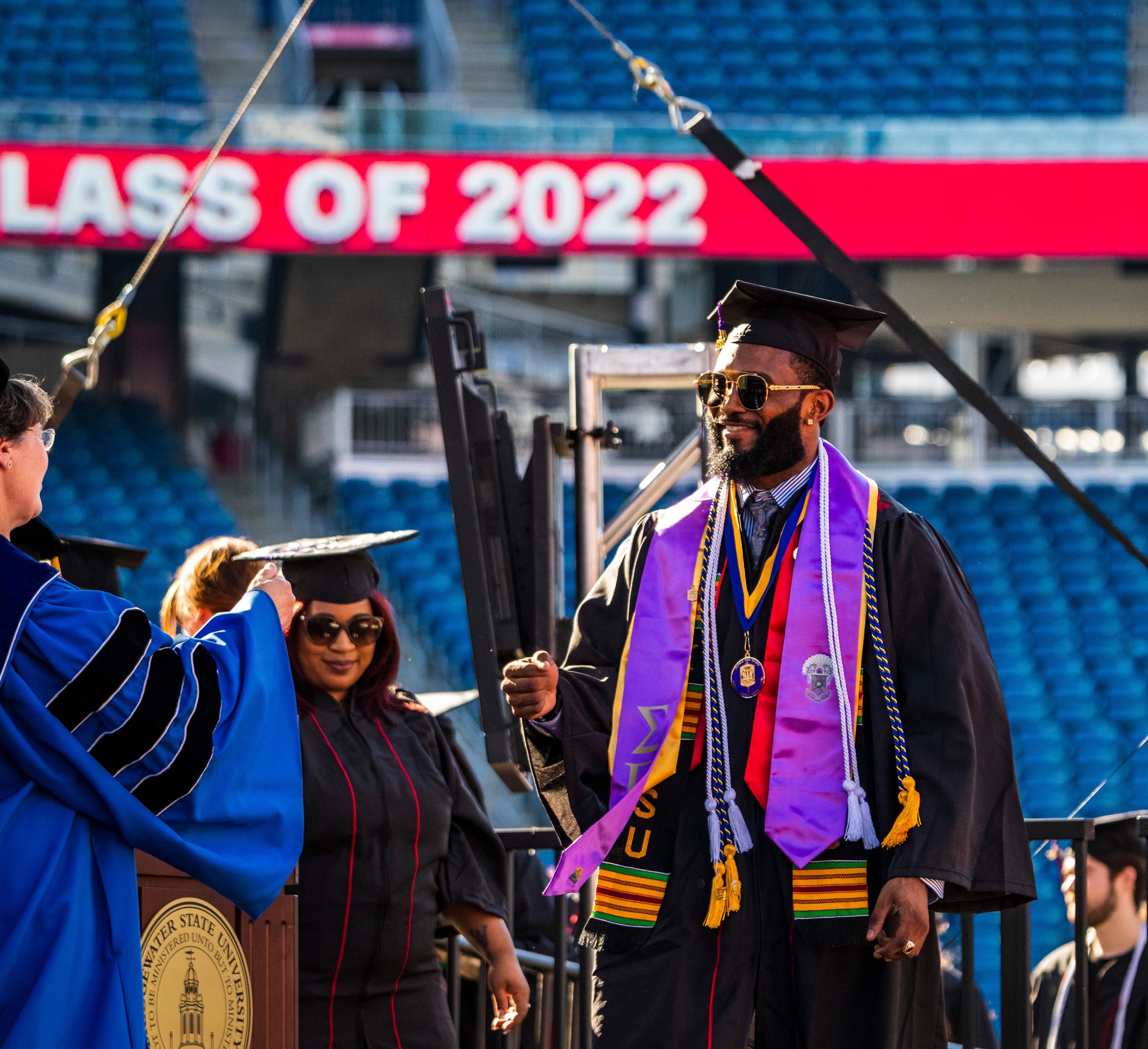Joseph Clark crosses the commencement stage and is greeted by an administrator.
