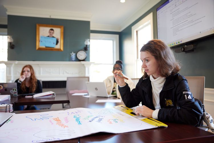 Inside the Martin Richard Institute for Social Justice, a student writes on a large piece of paper.