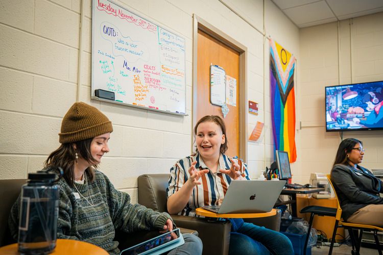 In the Pride Center, two people are sitting and conversing.