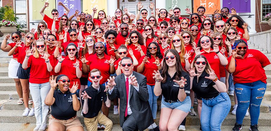    A large group of orientation leaders with President Clark making a bear symbol with their hands. 