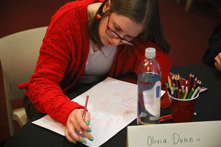 A student uses colored pencils to write on a piece of paper.