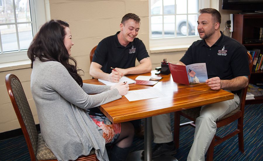 Three people sit at a table in the Veterans Center.