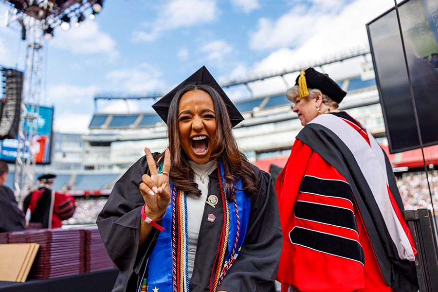 An excited student holds up two fingers after crossing the commencement stage.