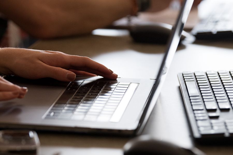 Close up of a laptop keyboard with two hands on it.