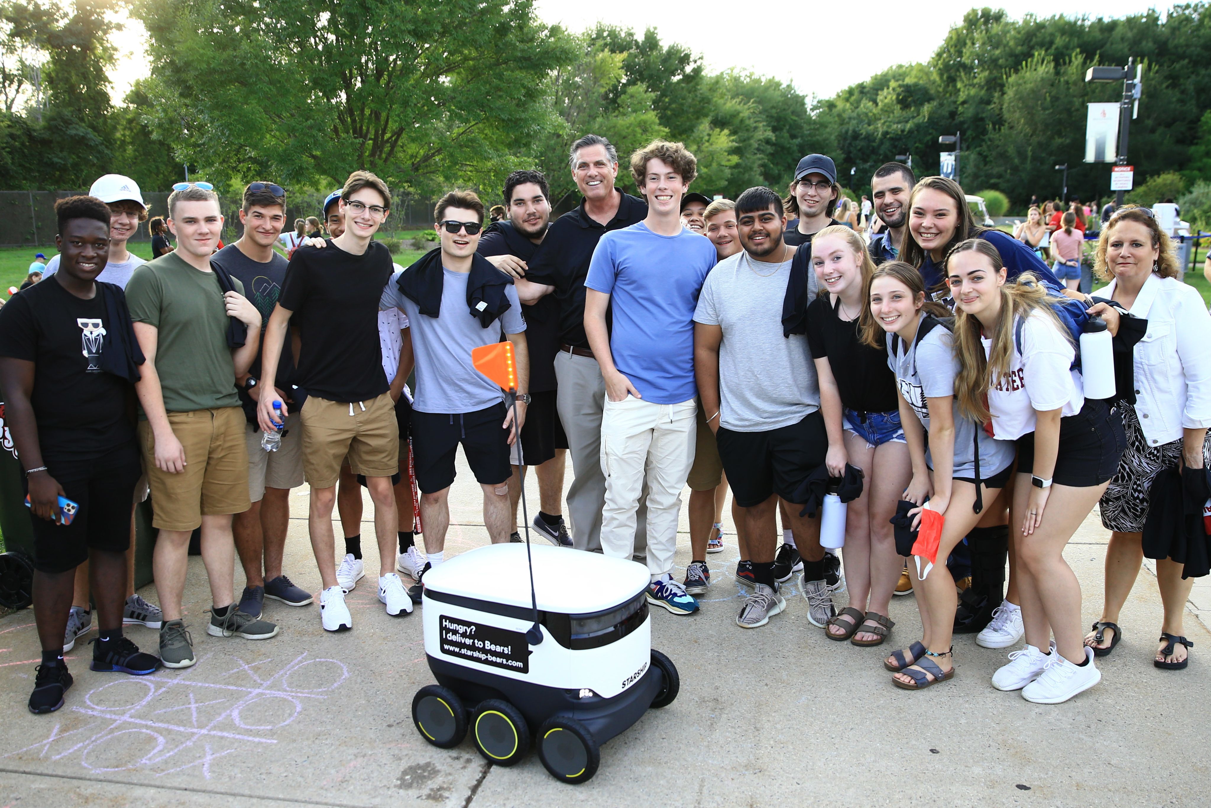 President Frederick W. Clark Jr., Esq., ’83, and students in University Park with one of BSU’s food delivery robots.